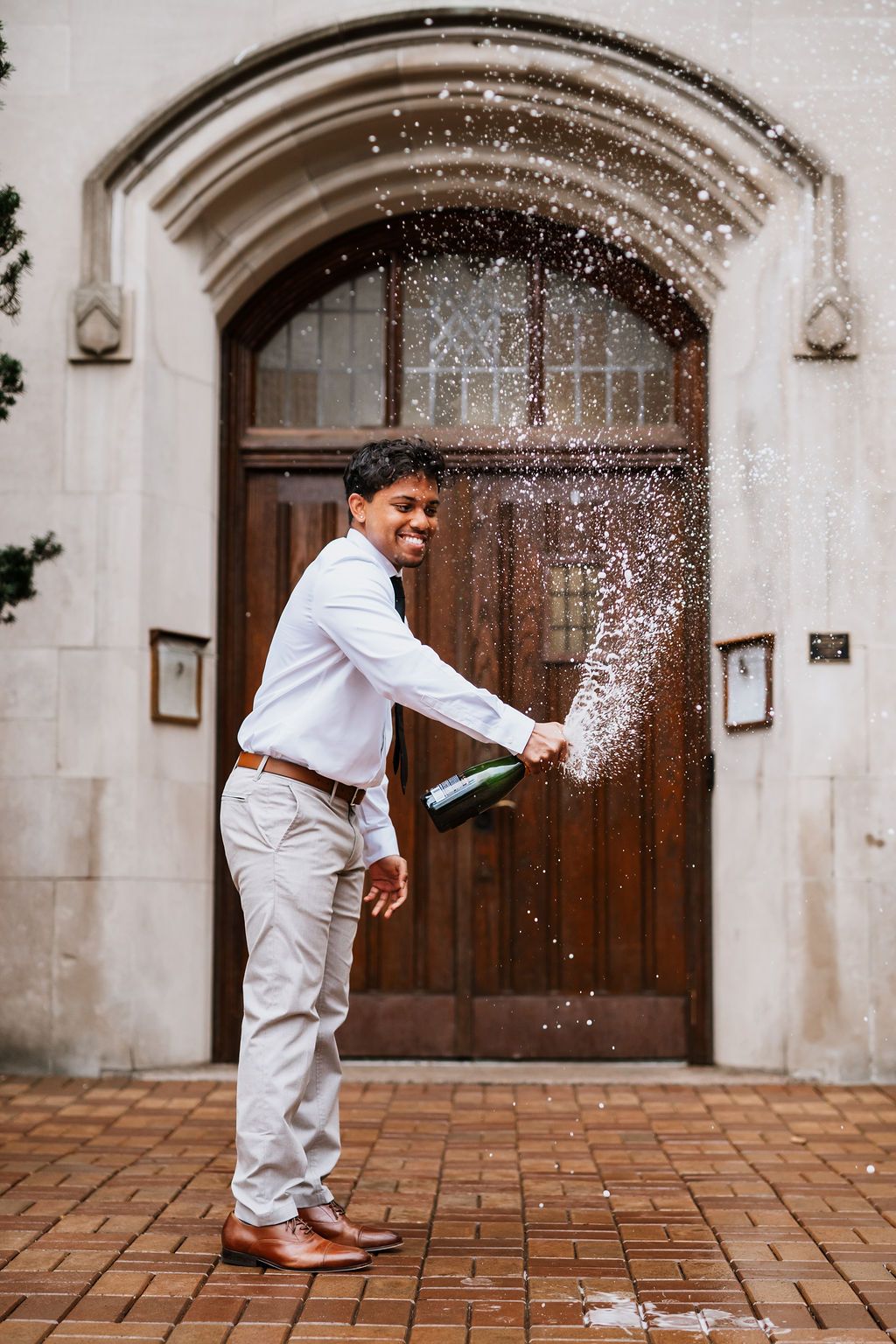 A sequence of five photos showing champagne being sprayed and splashing across a tiled courtyard entrance.