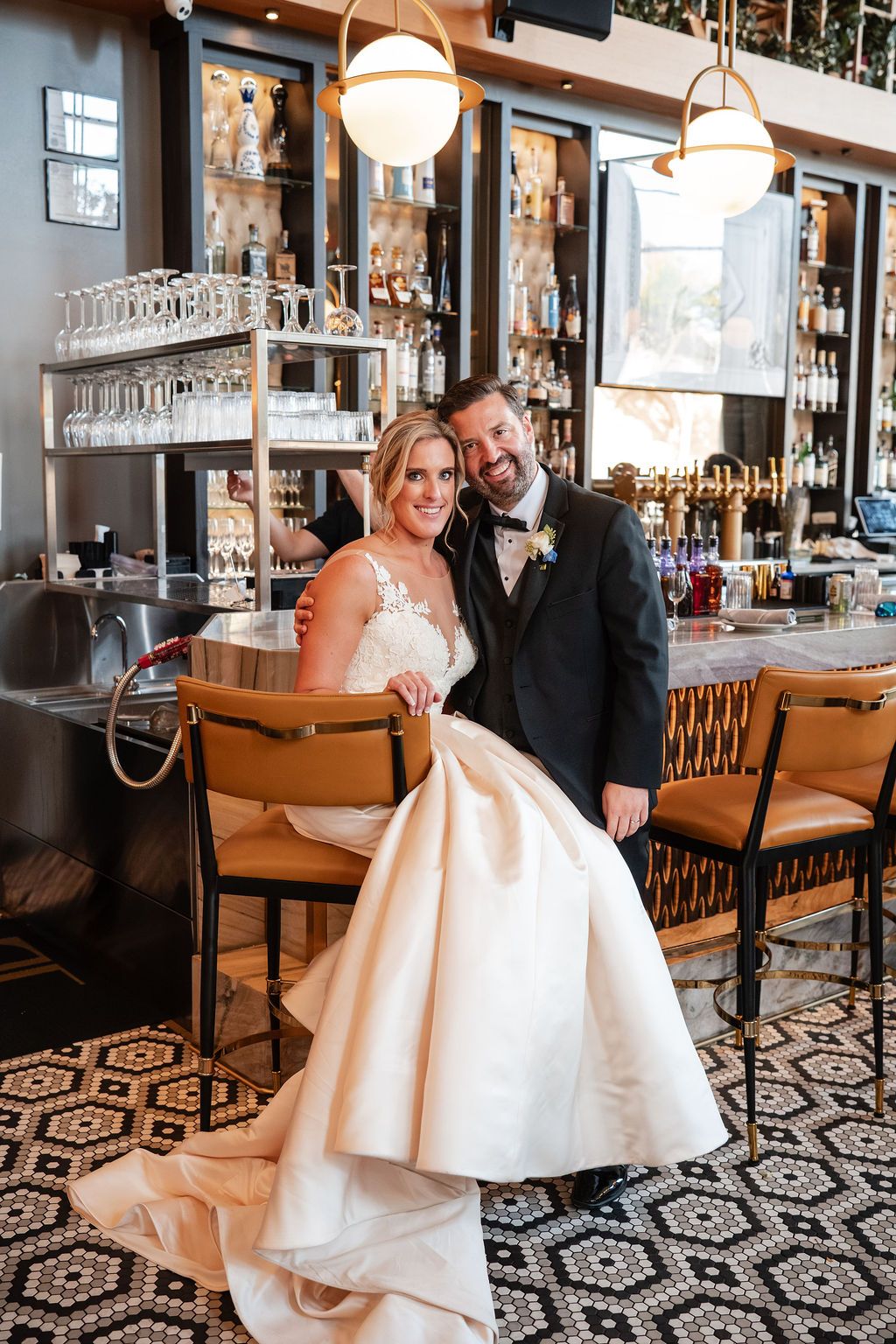 Wedding couple celebrating in stylish bar with geometric patterned floor and modern decor.