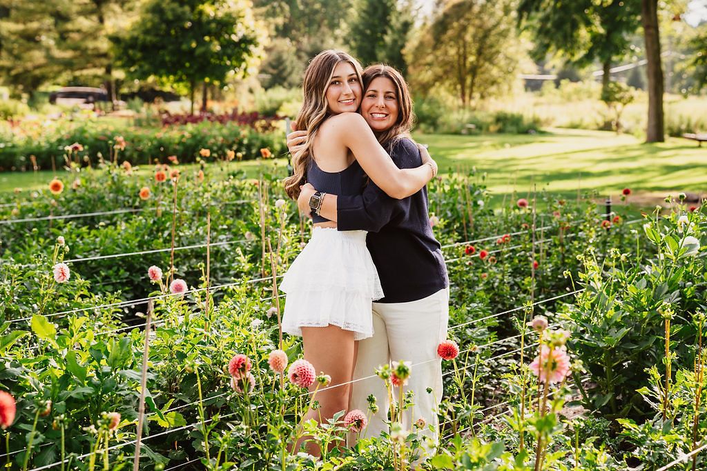 Candid friendship photography in a blooming garden with colorful flowers.