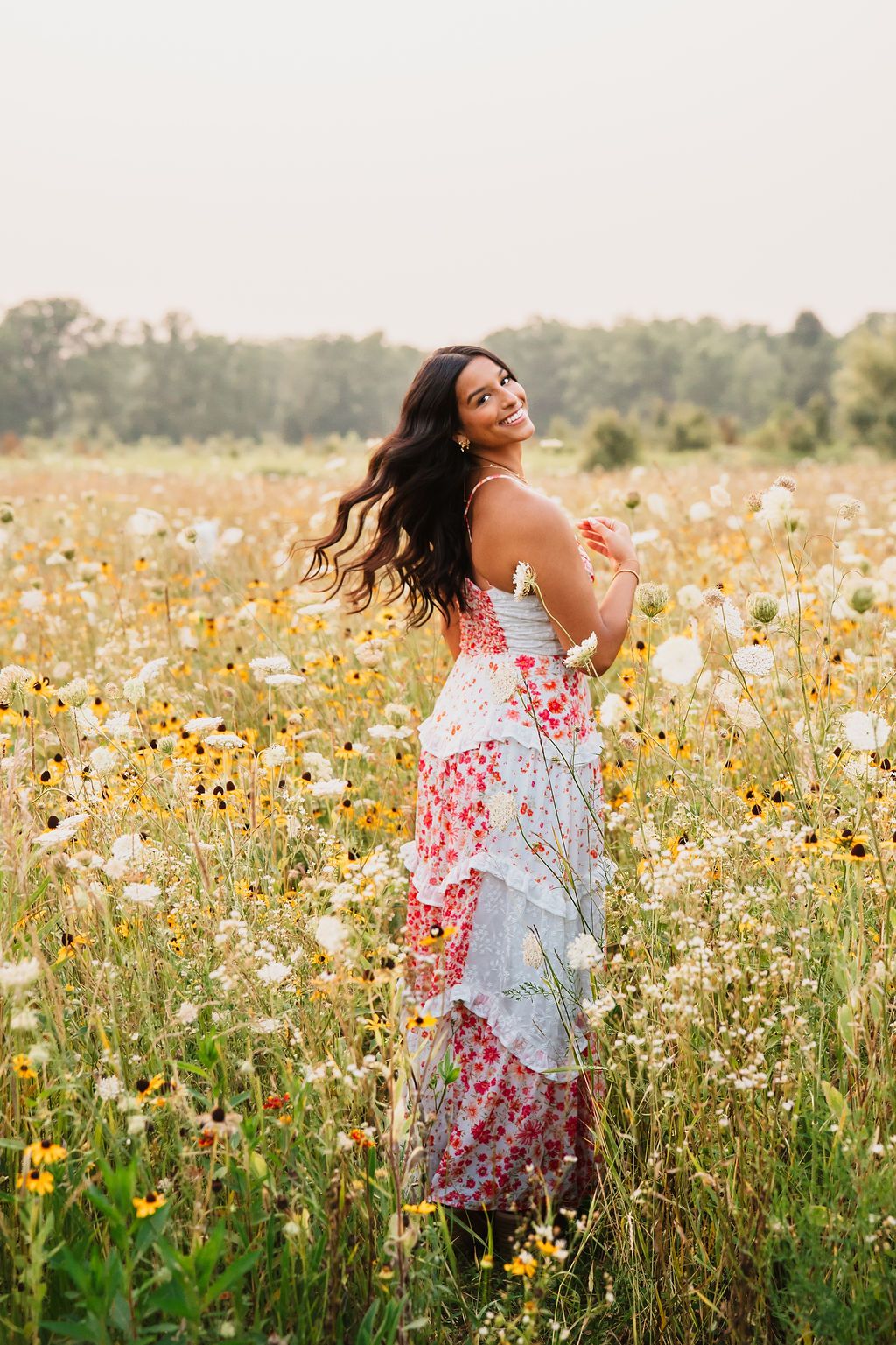 A flowy floral dress twirls gracefully in a summer wildflower meadow filled with yellow and white blooms.