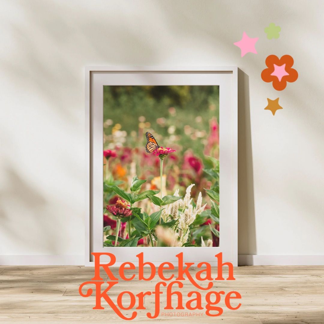 Framed print of a monarch butterfly on a pink flower in a colorful garden, leaning on a wood floor with Rebekah Korfhage text.