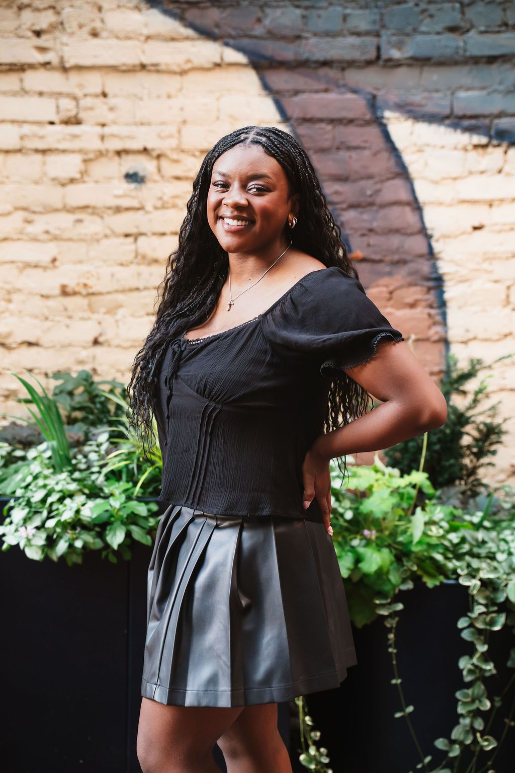 Fashion photoshoot against a brick wall showcasing a black and gray peplum top with ruffled details.