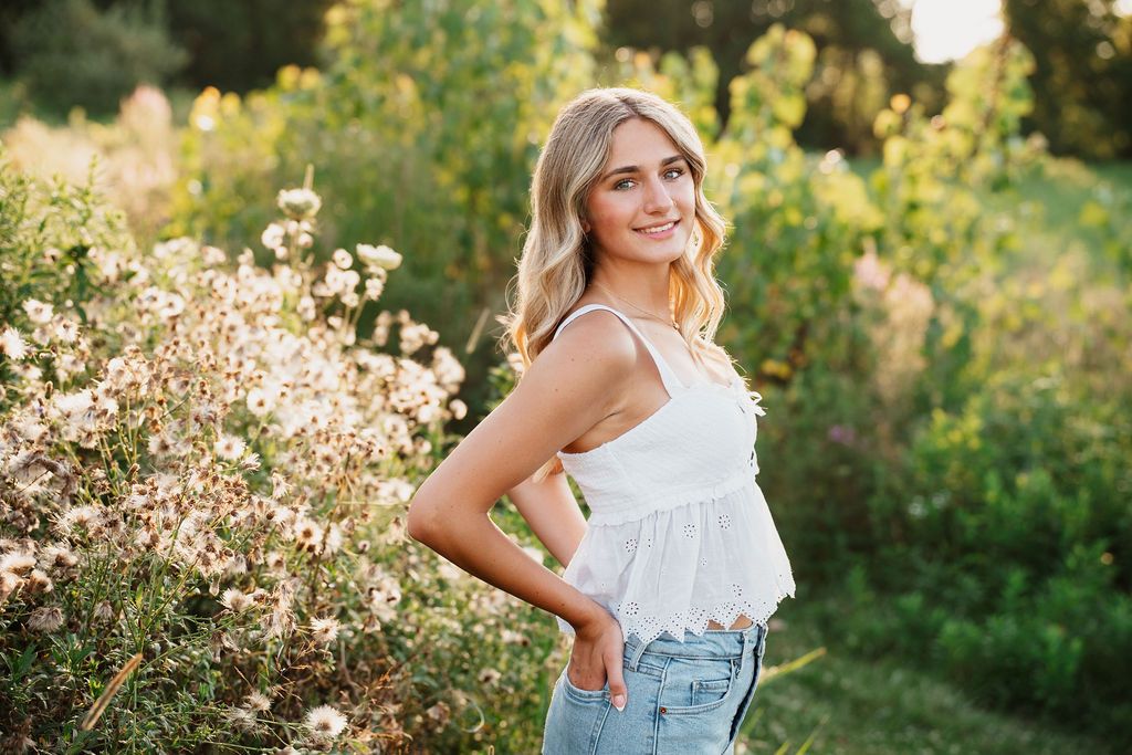 Dreamy golden hour portrait session in a wildflower field with soft natural lighting and summer fashion styling.