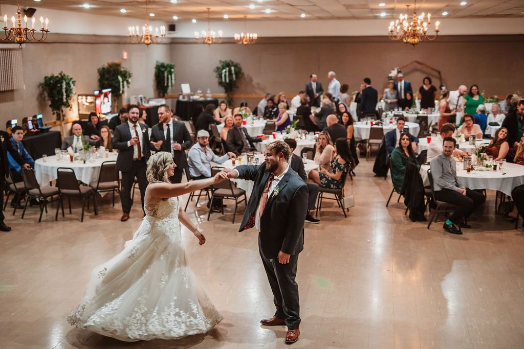 Wedding reception in an elegant ballroom with chandeliers and formal table settings.