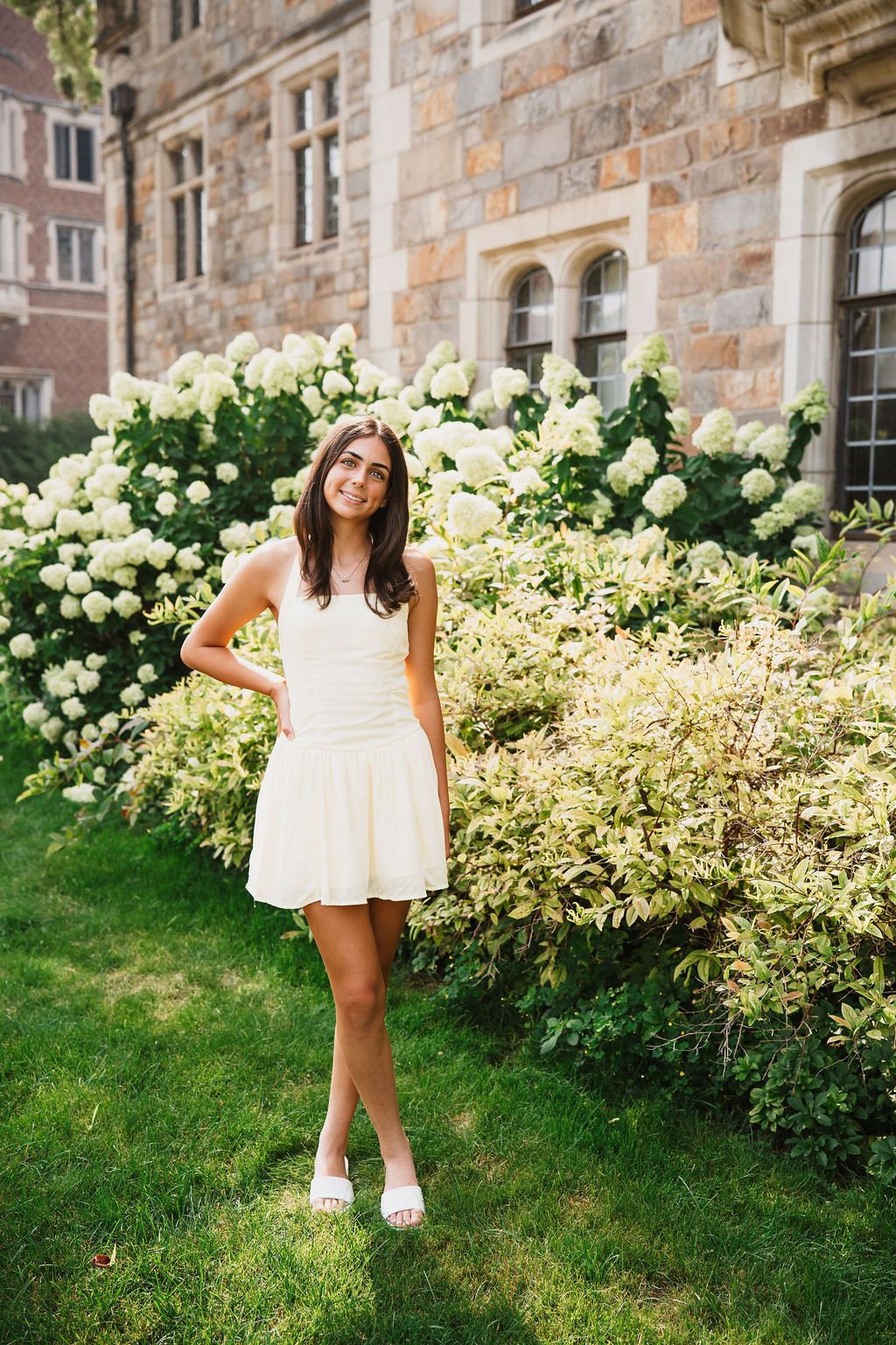 A white summer dress photographed against blooming hydrangea bushes and stone building exterior.