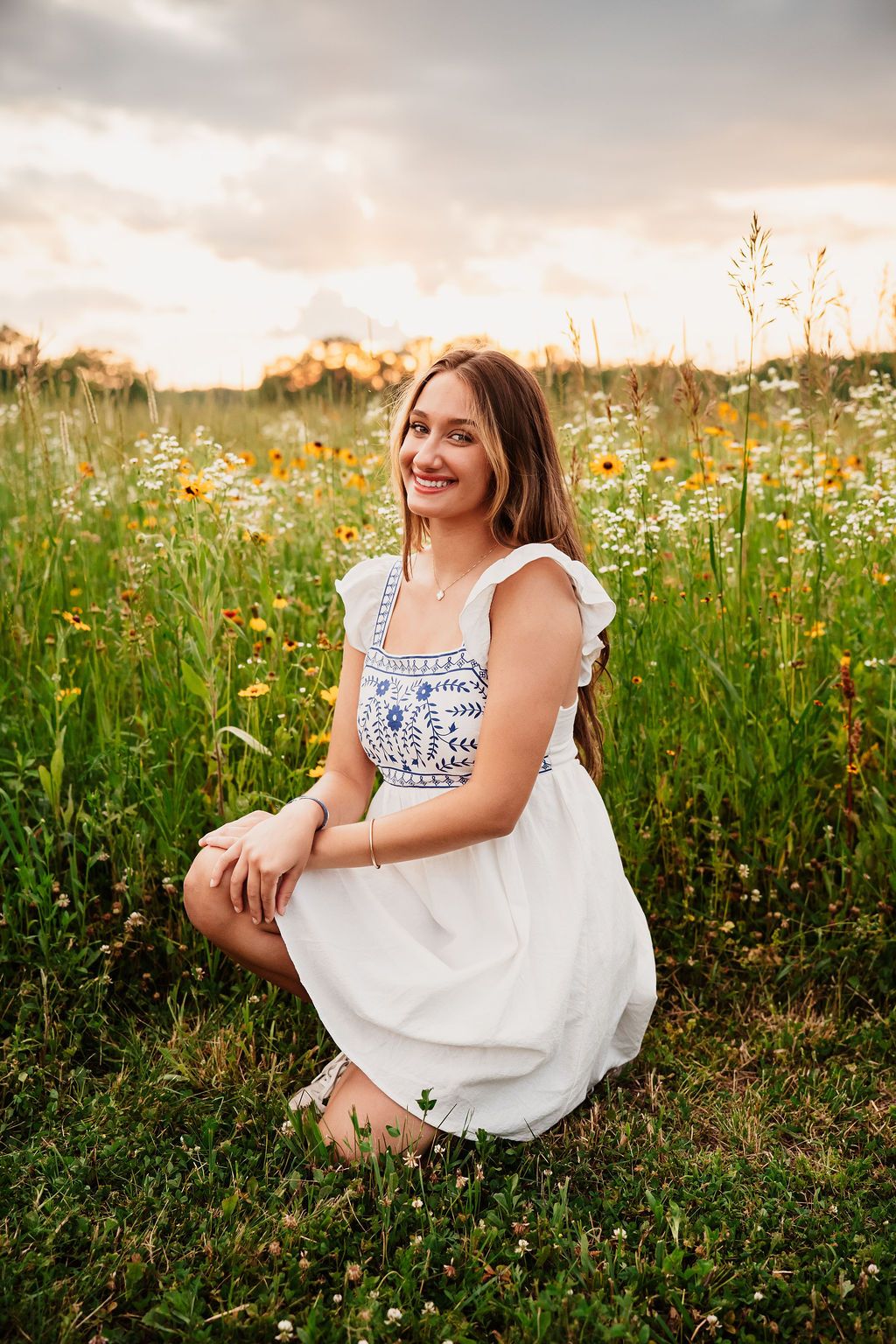 Natural light portrait in a blooming wildflower field wearing a white summer dress.