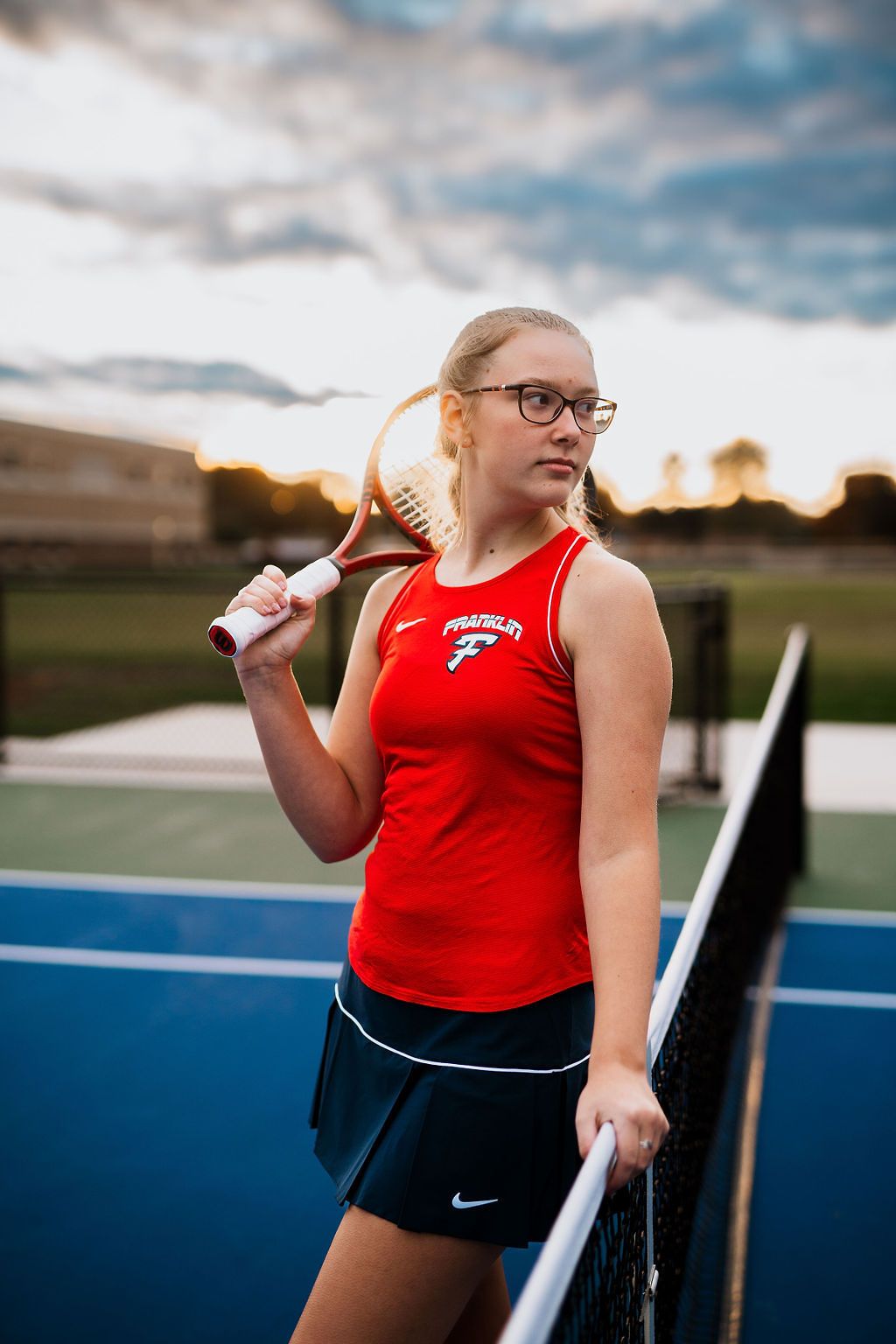 Athlete in red tank top practices shot put throwing technique at a sports facility.