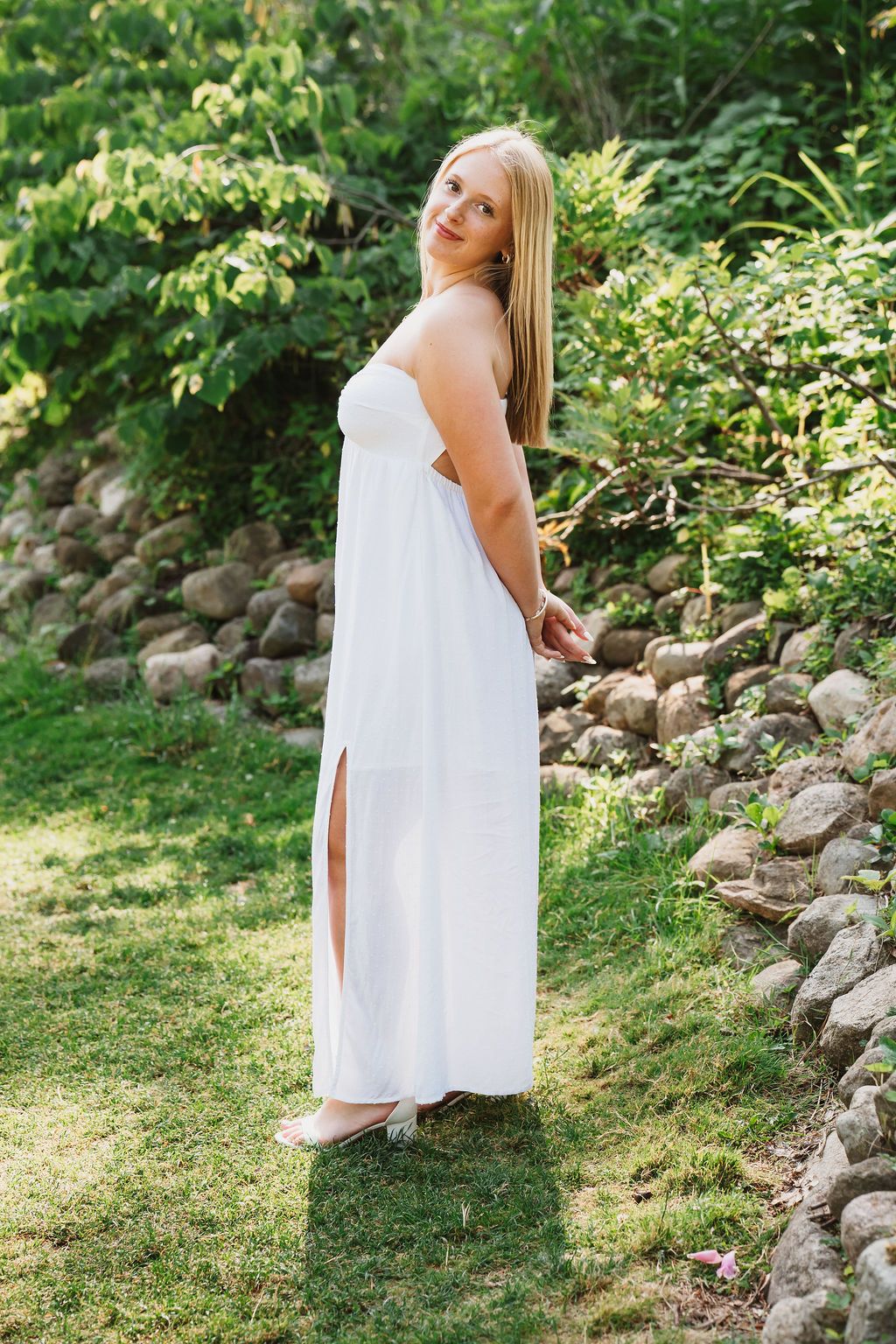 Summer garden photoshoot with stone landscaping and green foliage backdrop.