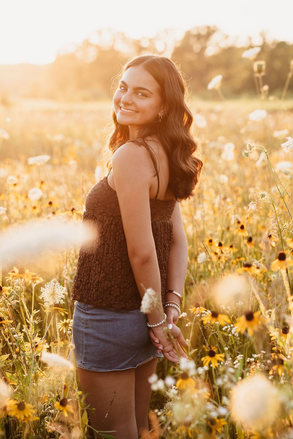Artistic portrait in a sunlit field of yellow wildflowers during sunset with warm tones.