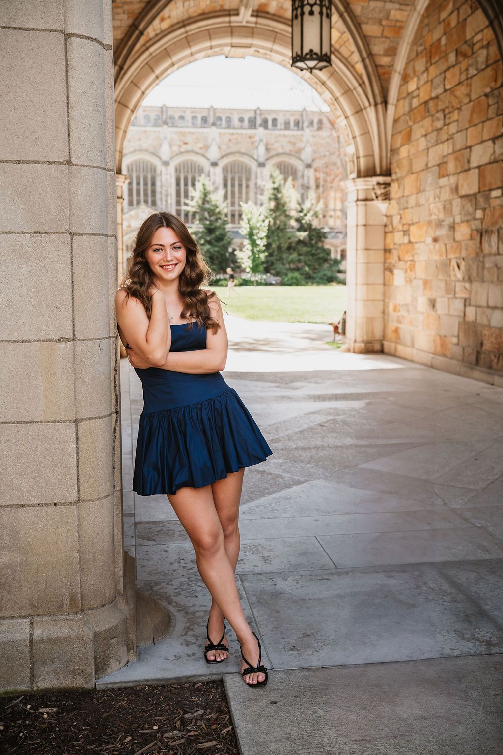 A series of photos in an elegant stone archway corridor showcasing a navy blue dress and architectural details.