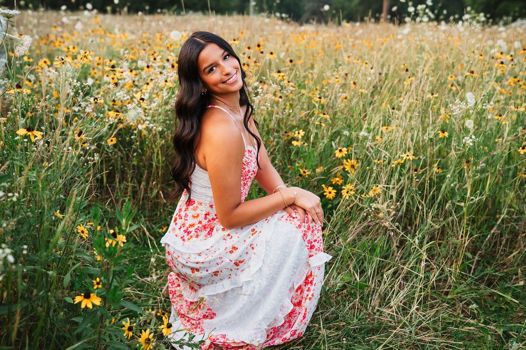 A floral sundress stands out against a summer meadow filled with yellow wildflowers and tall grass.