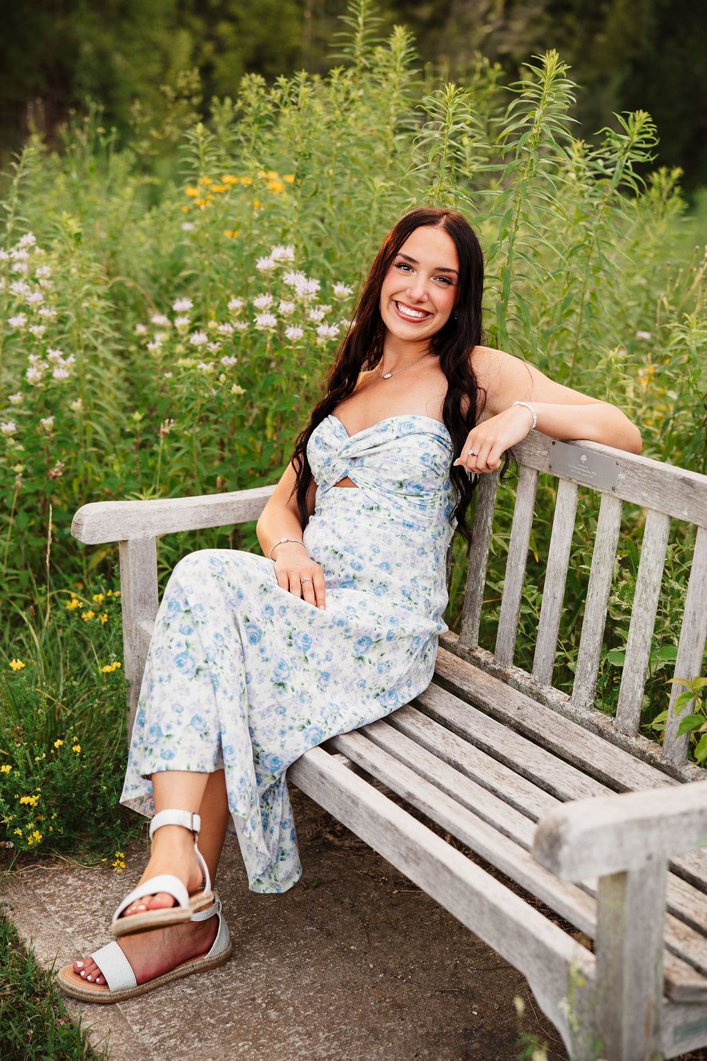 Wooden garden bench surrounded by blooming wildflowers and greenery.