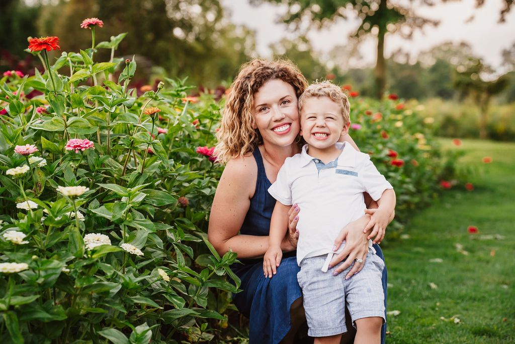 Outdoor family portrait session among blooming flowers in summer garden.