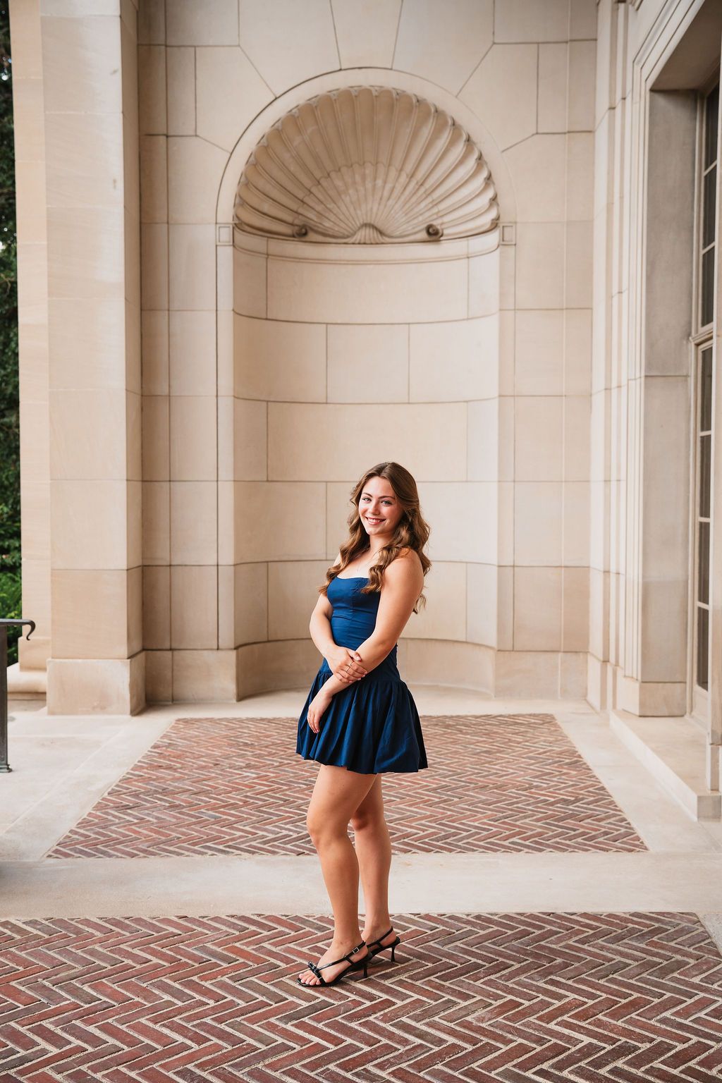 A series of photos showing someone in a navy blue dress posing playfully against a classical stone colonnade.