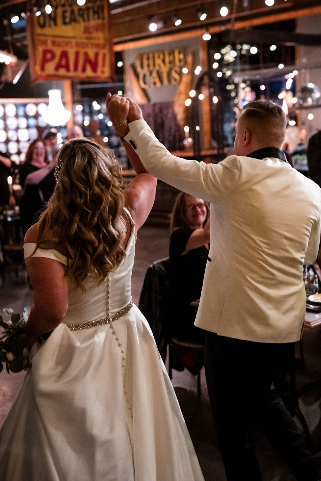 Wedding celebration on dance floor with vintage carnival decor and lighting.