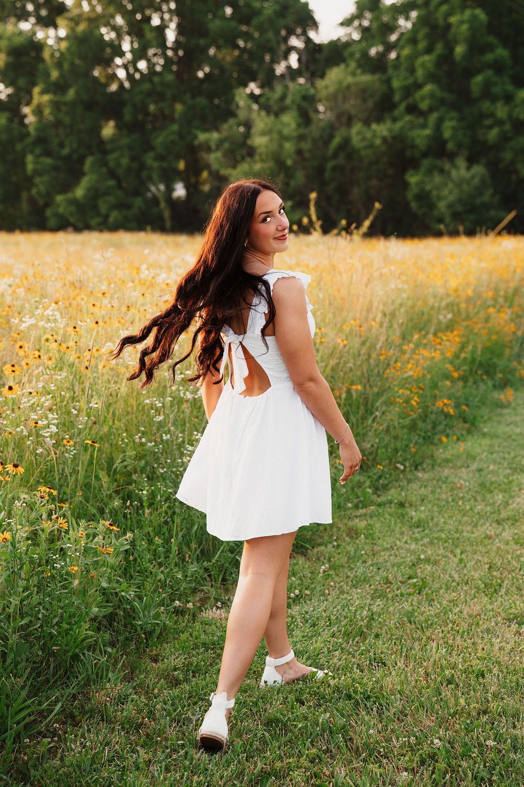 Dancing through a wildflower field at sunset in flowing white dress.