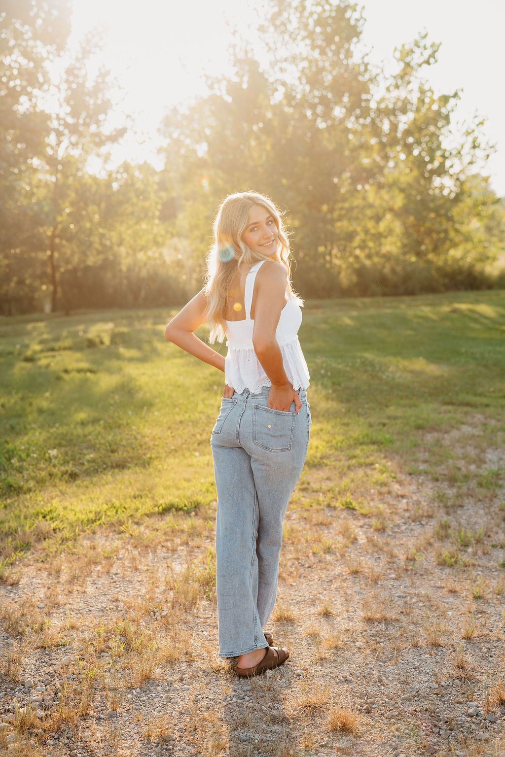 Casual summer outfit featuring light wash denim and white top photographed in warm evening sunlight.