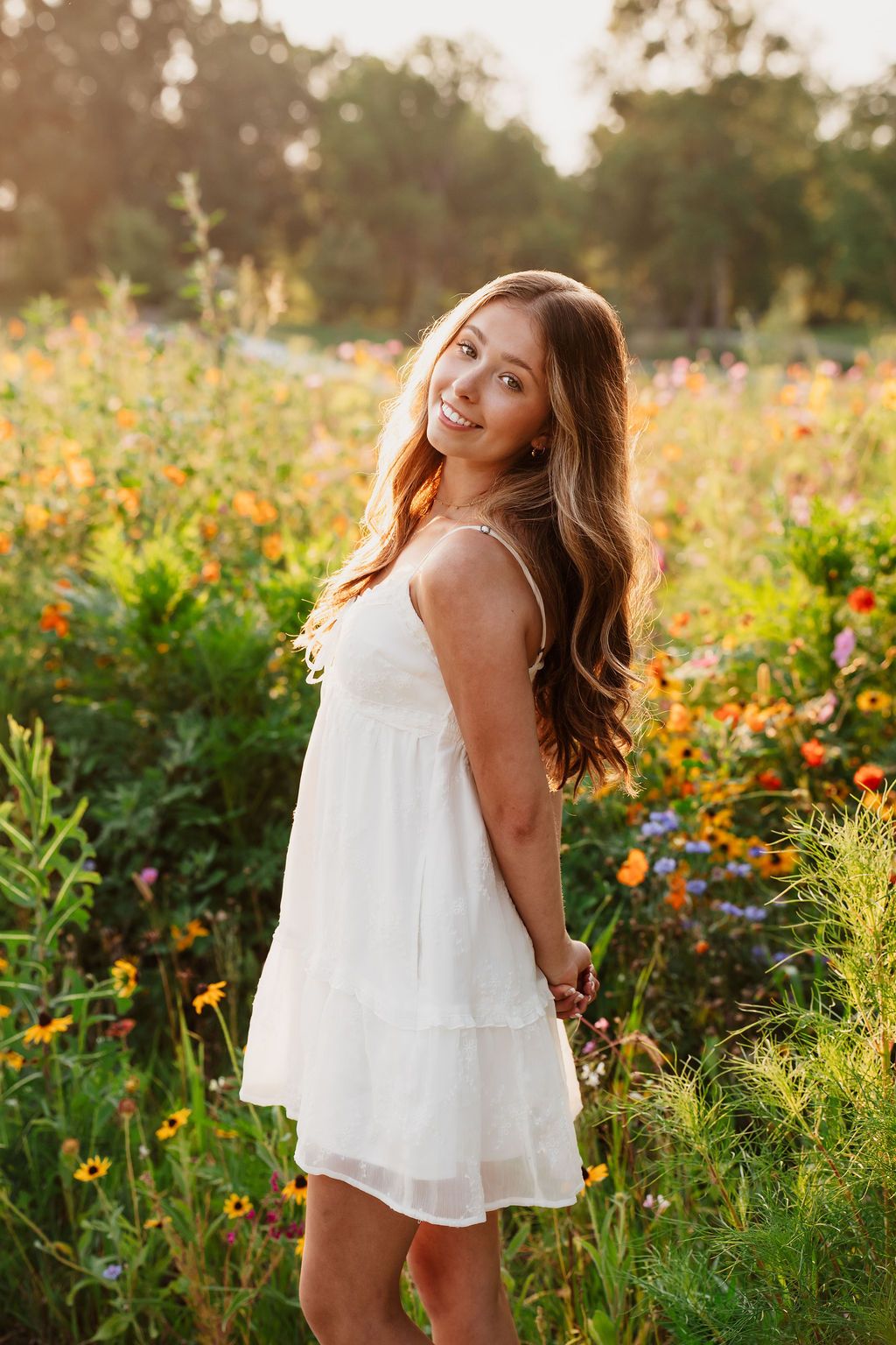 A series of four photos showing a white summer dress in a vibrant wildflower field at golden hour.