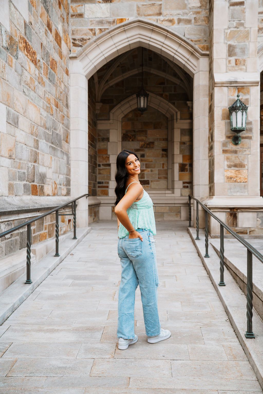 Light blue overalls and white sneakers create a casual look against historic stone architecture.
