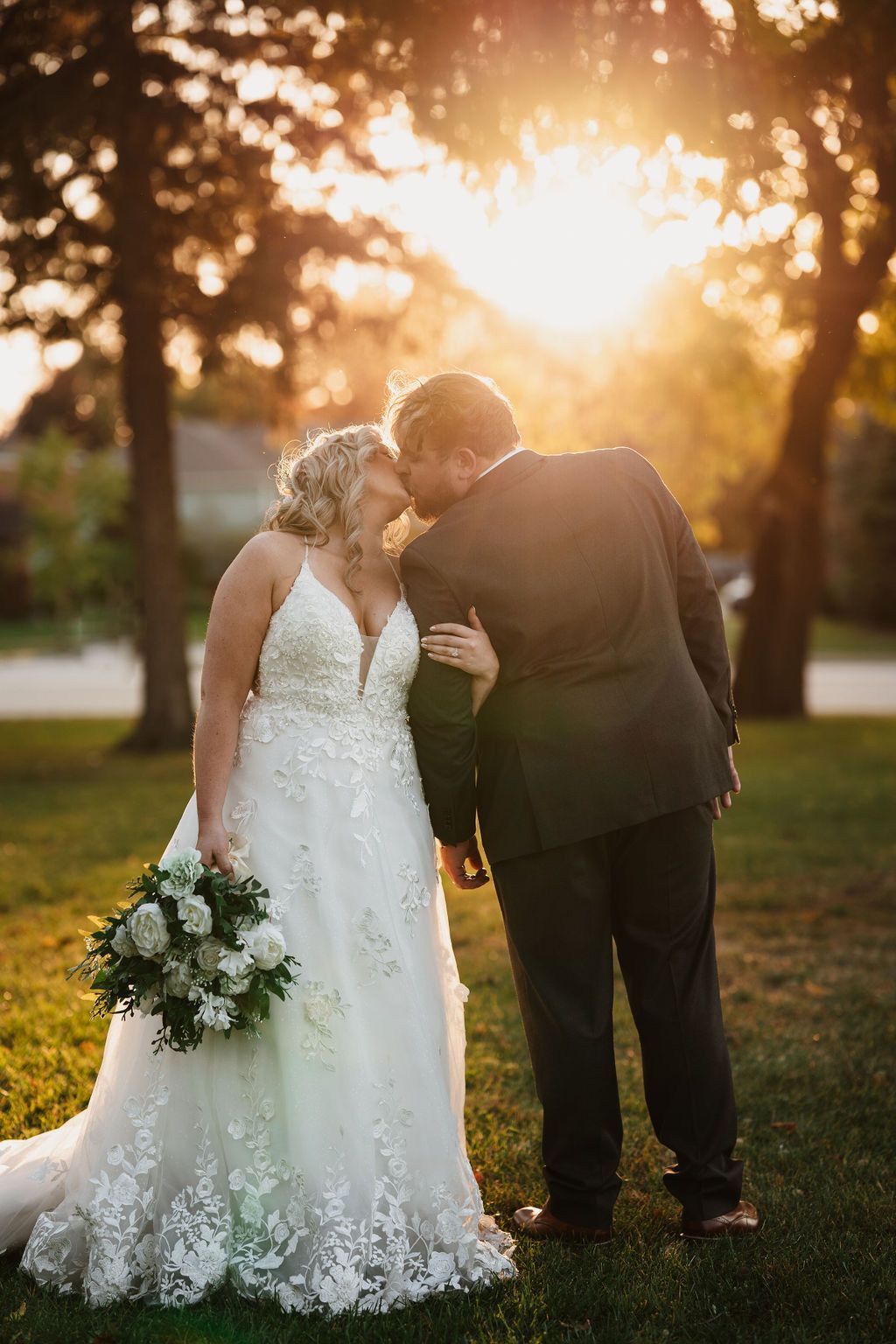 Golden sunset wedding portrait with couple silhouetted against warm evening light.