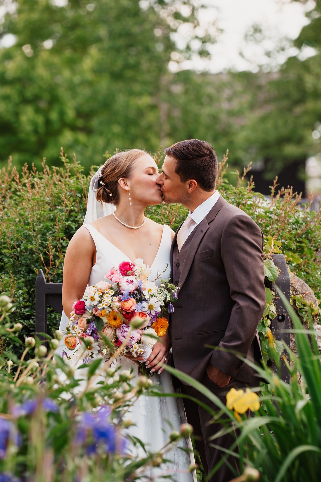 Garden wedding portraits among colorful iris flowers and lush greenery.
