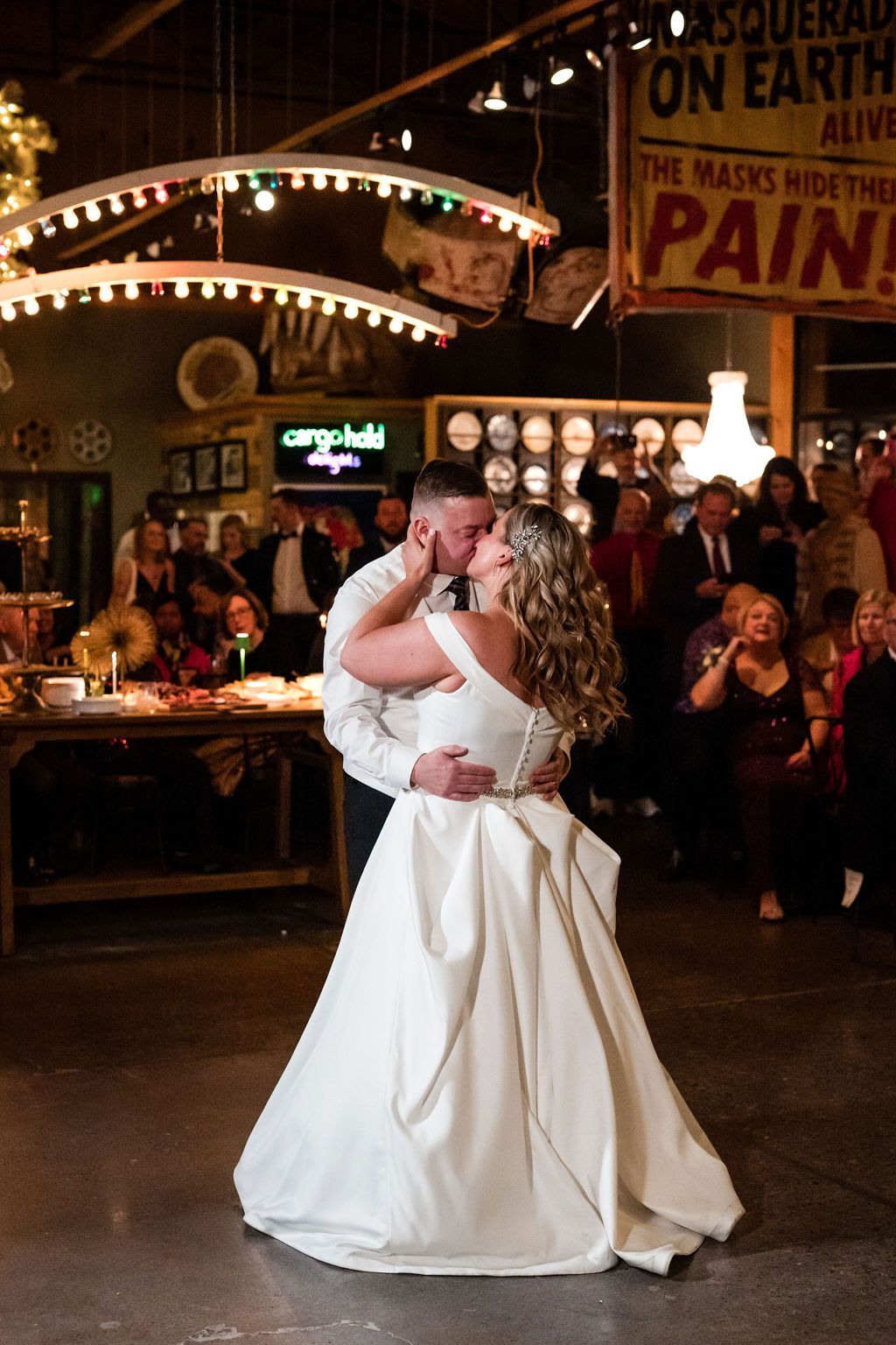 Wedding couple dances under vintage carnival signs and string lights.