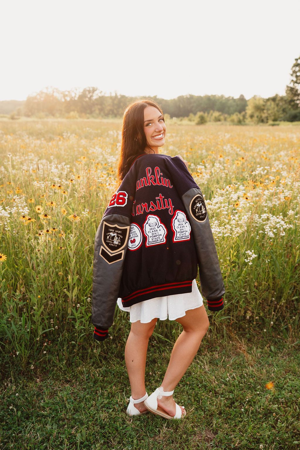 Varsity letterman jacket posed in a blooming wildflower meadow at sunset.