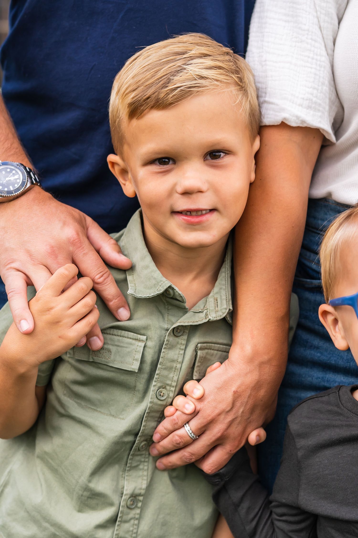 Close up portrait in outdoor setting with gentle hands providing comfort and support. Mini sessions for metro Detroit families
