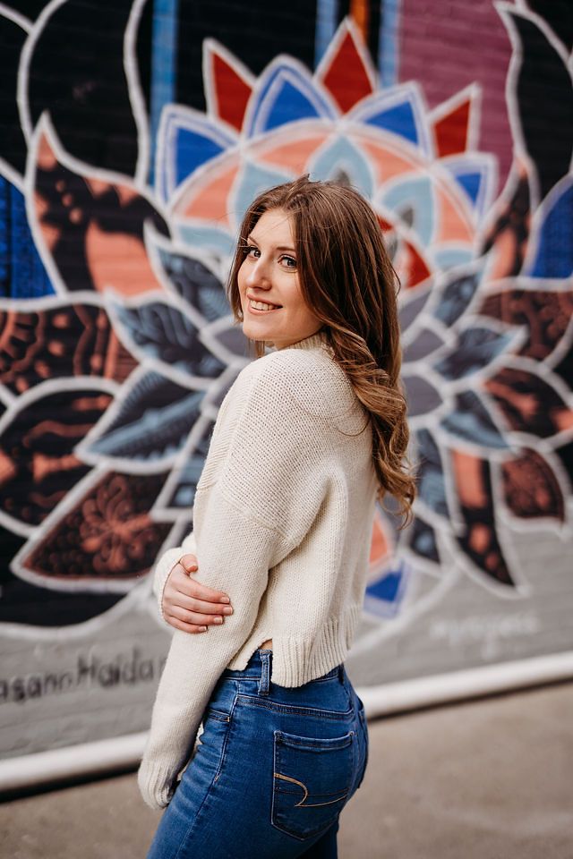 Urban portrait session against colorful graffiti wall featuring geometric flower designs.