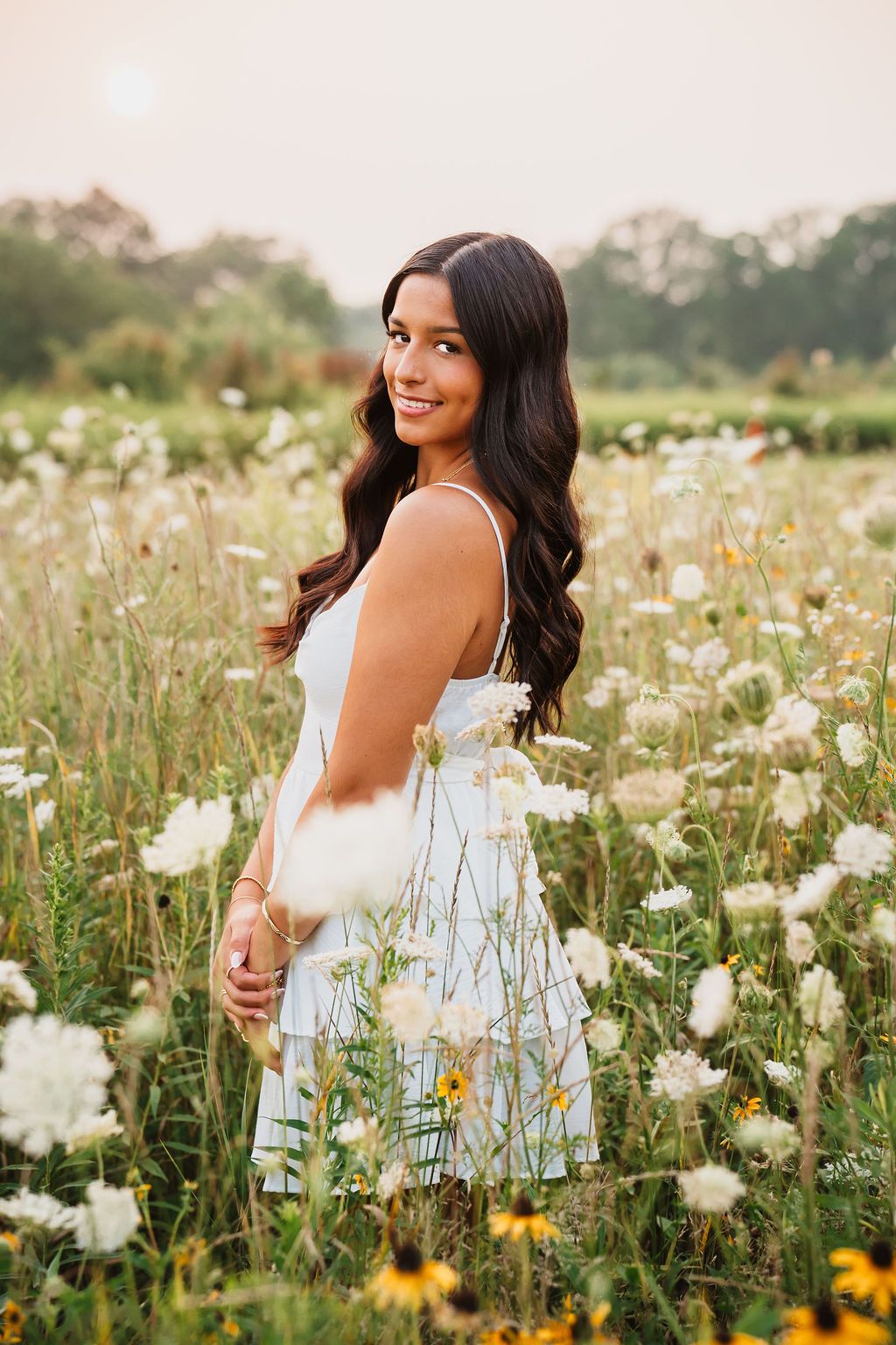 Summer portrait session among white cosmos flowers and yellow wildflowers in a natural meadow.
