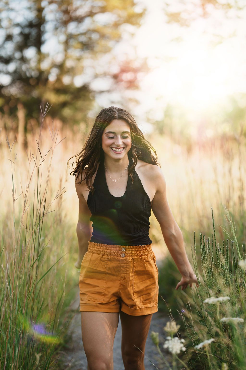 A joyful moment captured in tall golden grass during sunset with orange shorts and a black top.