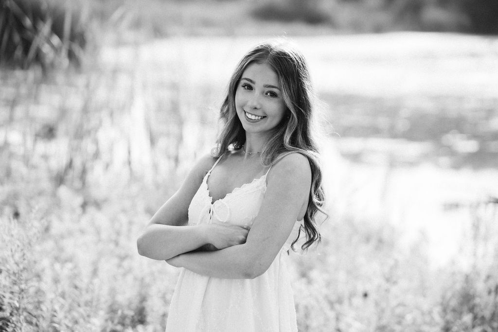 Black and white portrait series showing a woman in a white dress posing joyfully in an outdoor meadow setting.