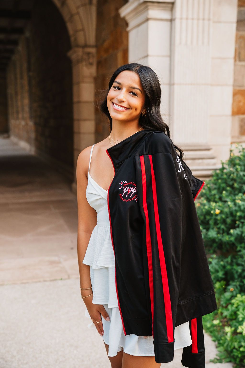 A graduation photoshoot featuring a white summer dress and black graduation gown with red stripes.