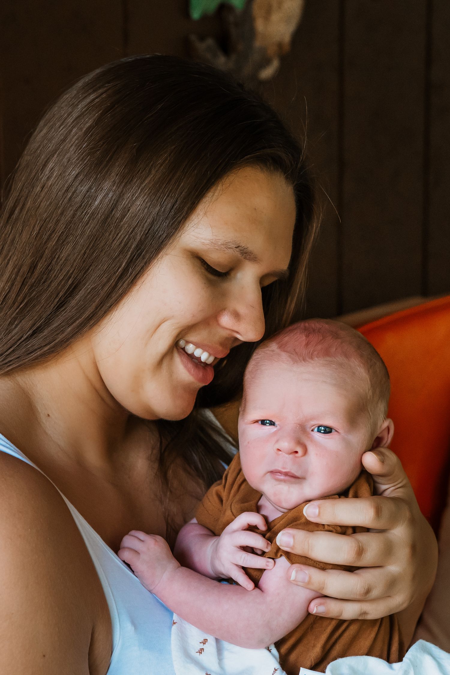 Smiling young mother tenderly holds her newborn baby, sharing a precious bonding moment together.