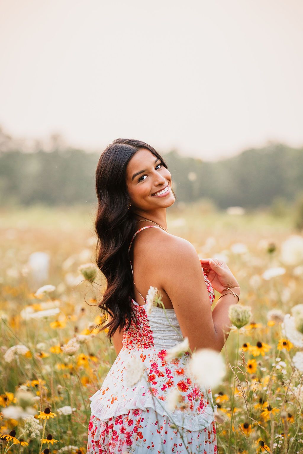 Joyful summer portrait in a field of yellow wildflowers with a red and white floral dress catching the evening light.