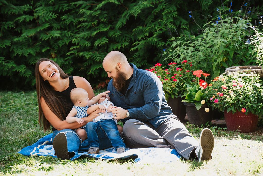 Family members laying on a blue blanket during an outdoor photo session.