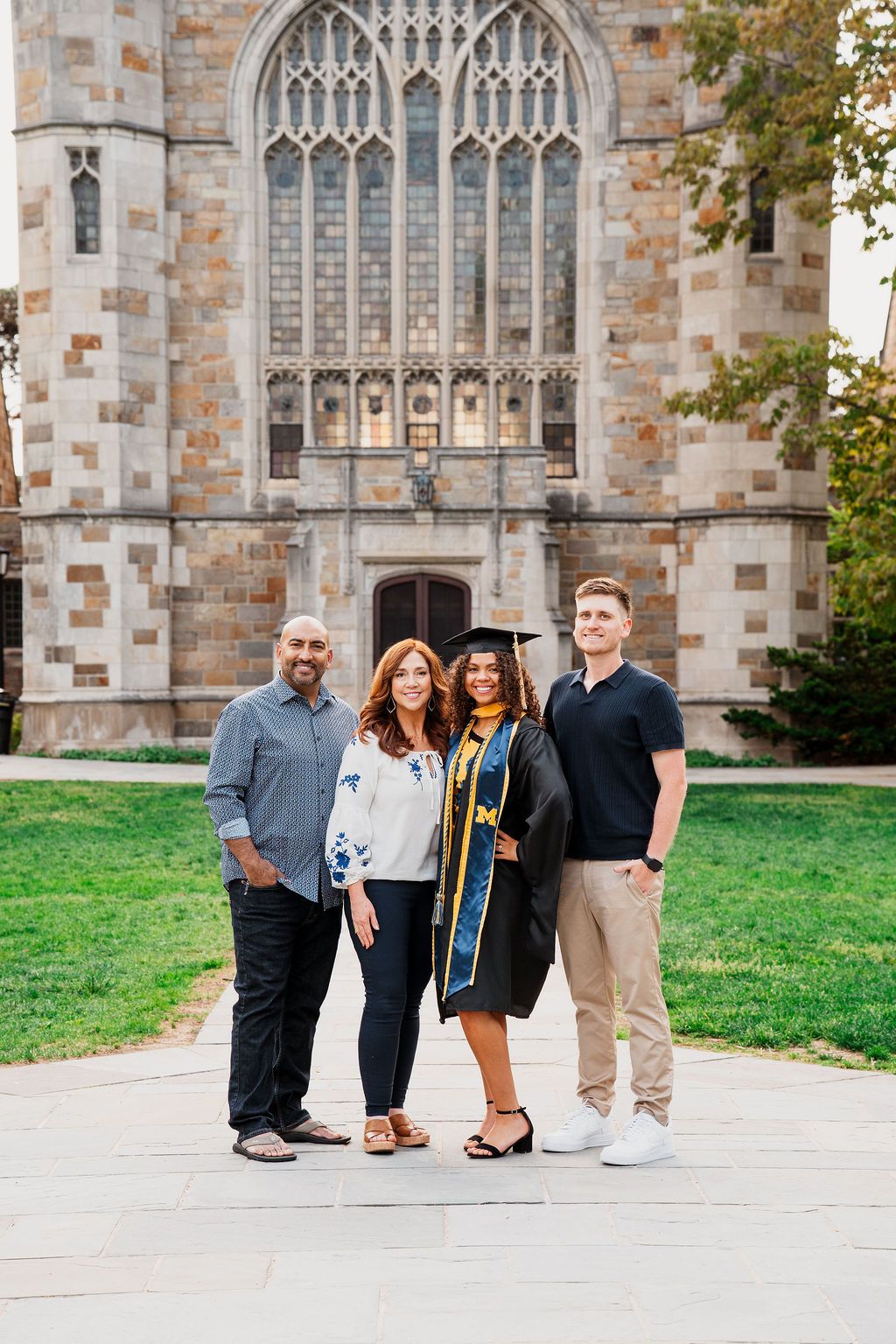 A group stands together in front of a gothic stone church with ornate architecture and stained glass windows.
