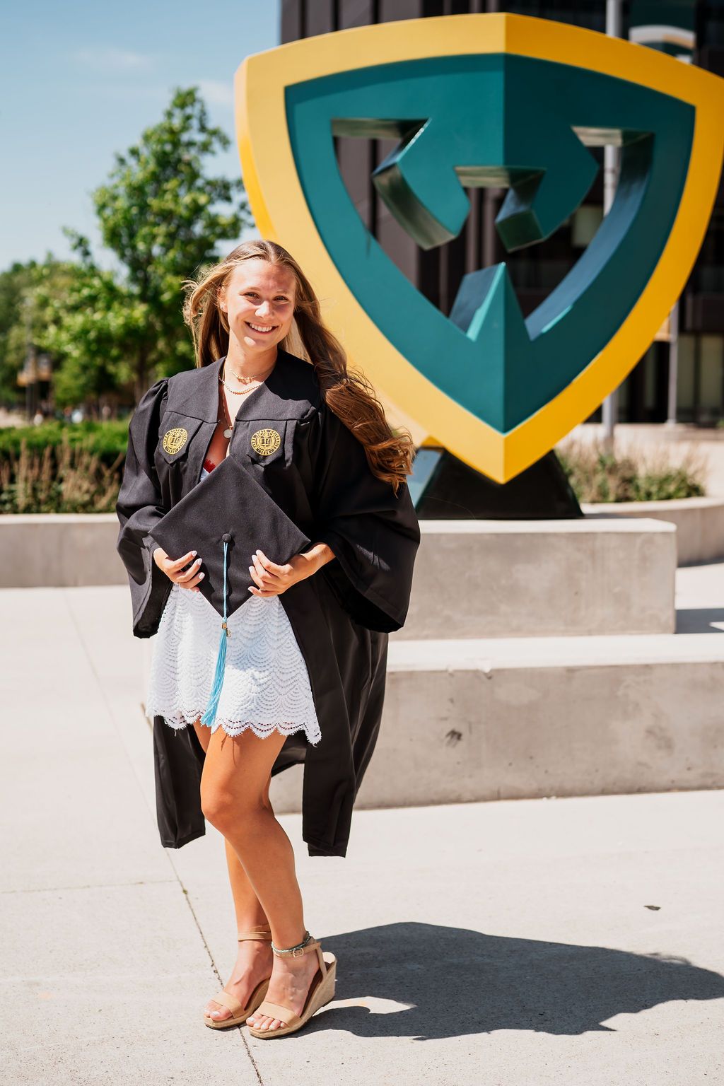 Graduation photos showing gold and teal university shield decorations against concrete backdrop.