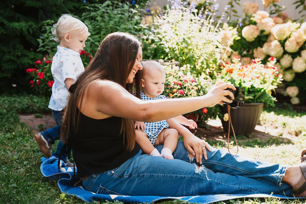 Summer garden photo session with flowering bushes and blue blanket setup.