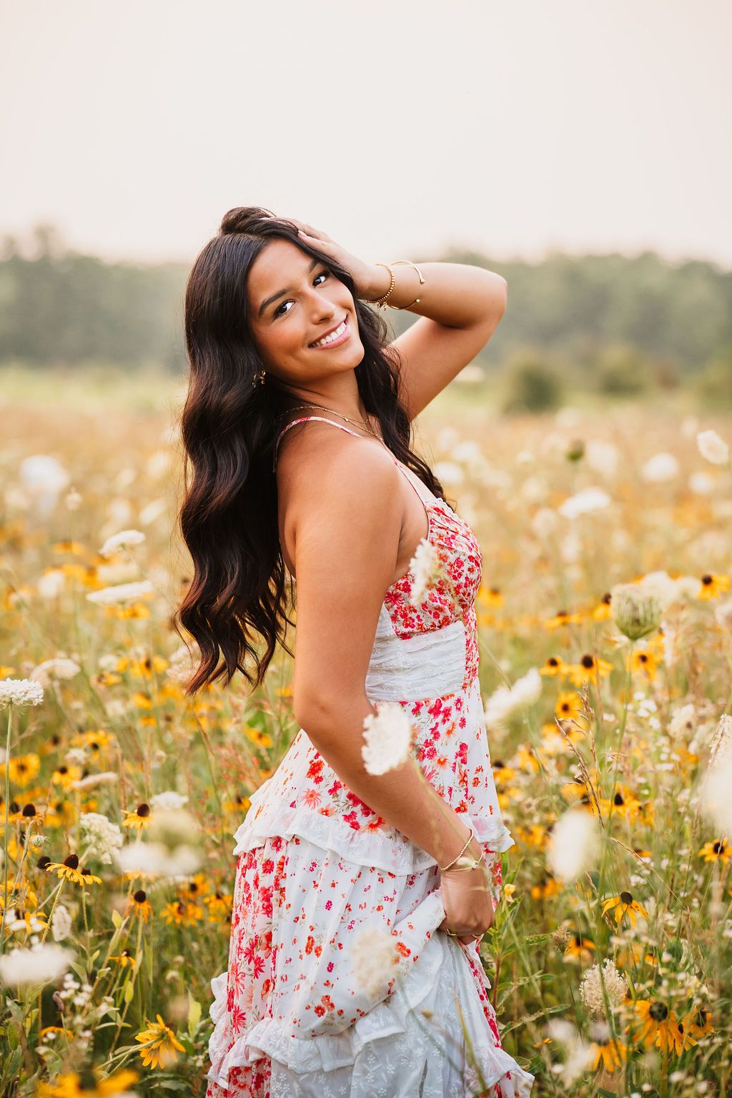 A floral sundress photoshoot in a field of yellow wildflowers and white cosmos flowers.