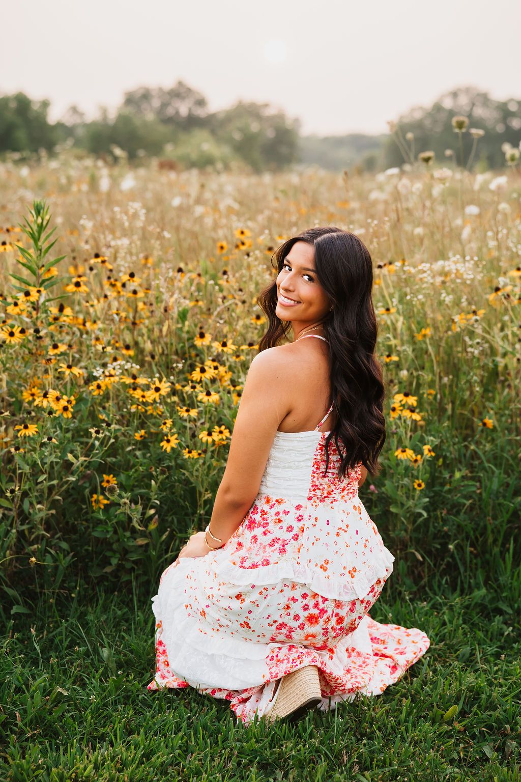 A white and red floral sundress stands out beautifully against a wildflower meadow filled with yellow blooms at sunset.