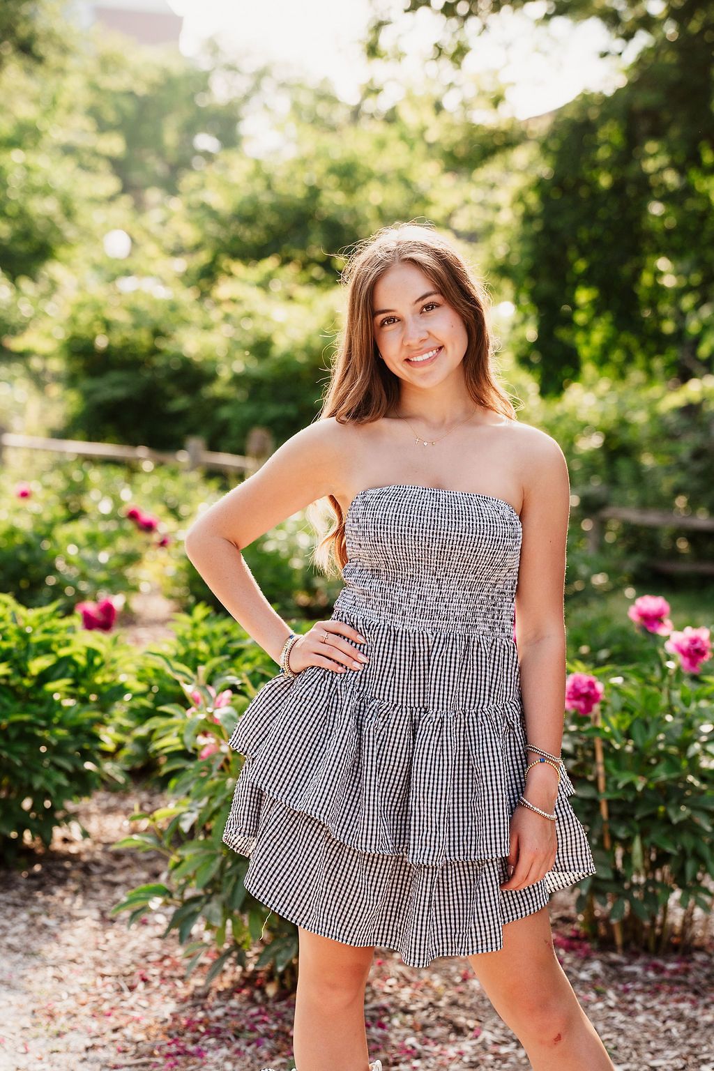 Summer fashion photography featuring a gingham dress in a garden setting with pink flowers. Nichols Arboretum Senior Photos June
