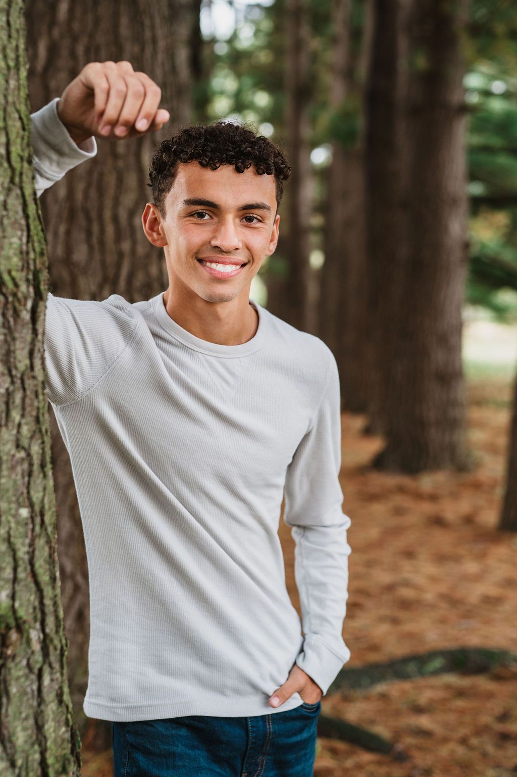 Portrait session in a wooded area with pine trees and natural lighting.