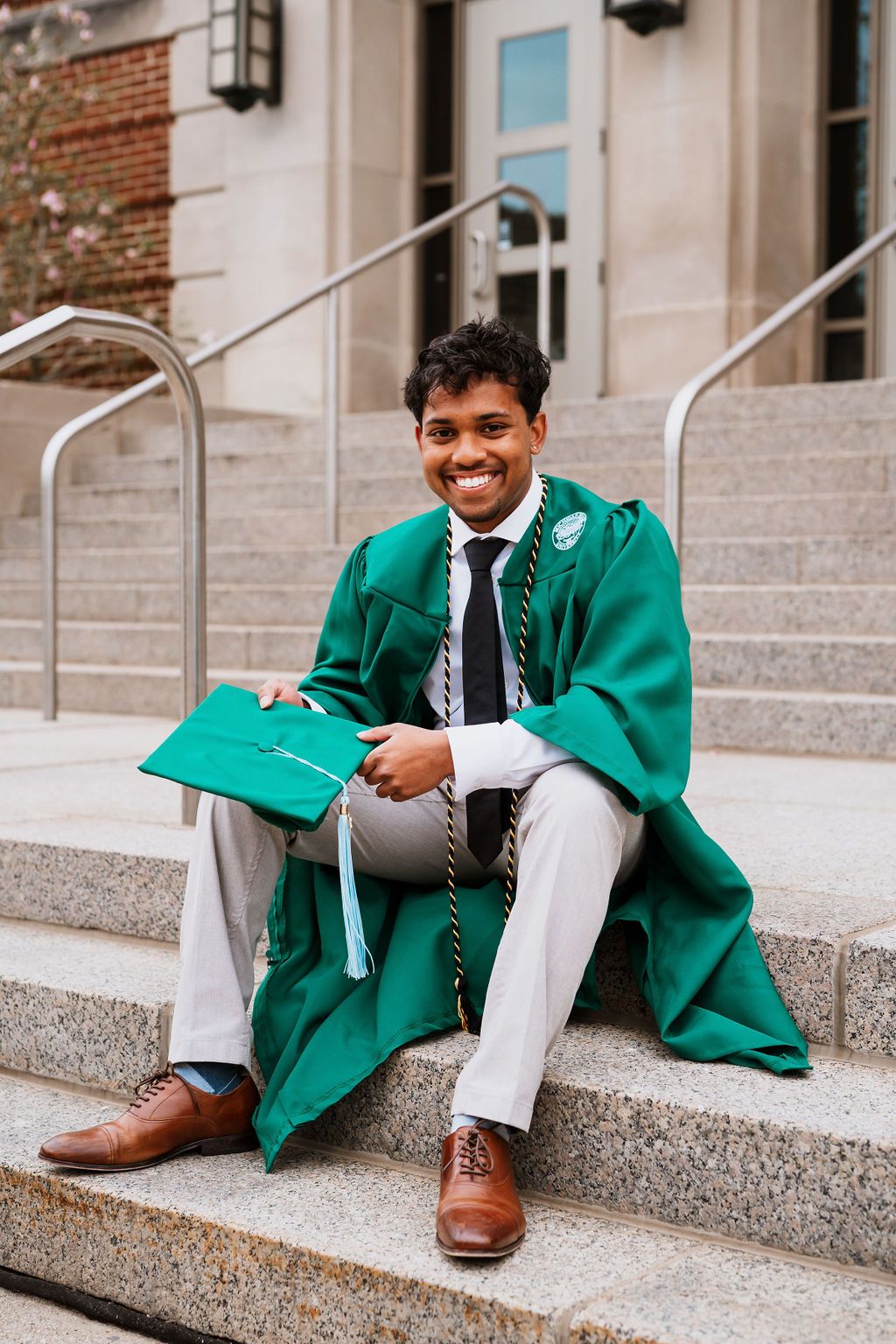 Graduate in bright green graduation gown sits on concrete steps smiling in three different poses.