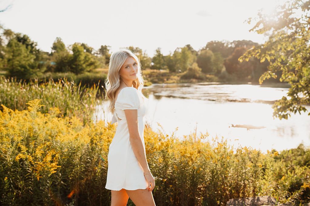 Golden hour nature photography with sunlit meadow and water views in the background.