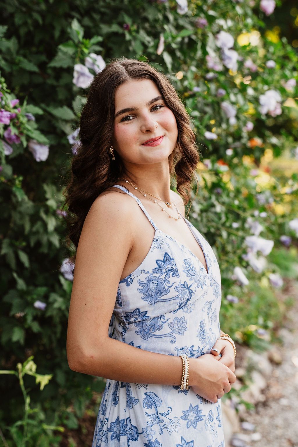 Summer portrait in a garden with blooming flowers featuring a blue and white floral dress.