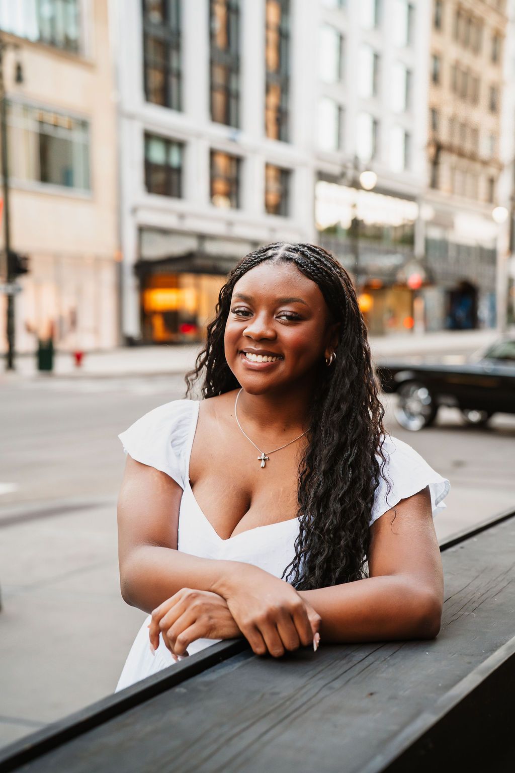 A smiling woman in a white top poses for a series of casual outdoor portraits on a city street.