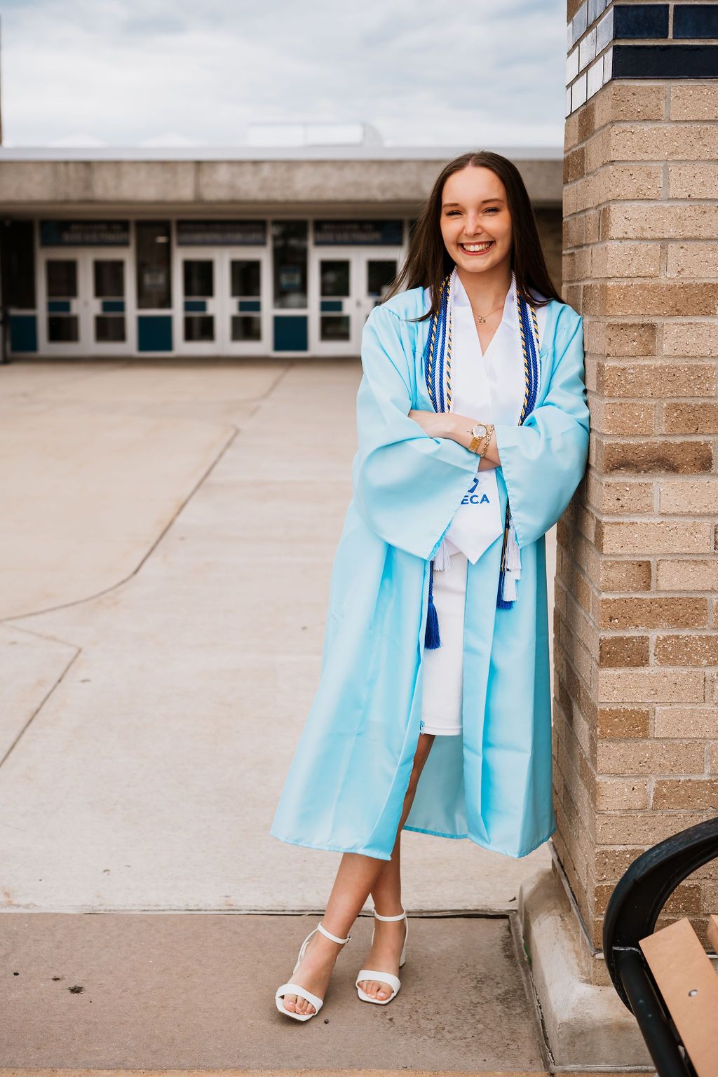 A series of graduation photos showing someone in a light blue blazer and white dress posing against a brick wall.