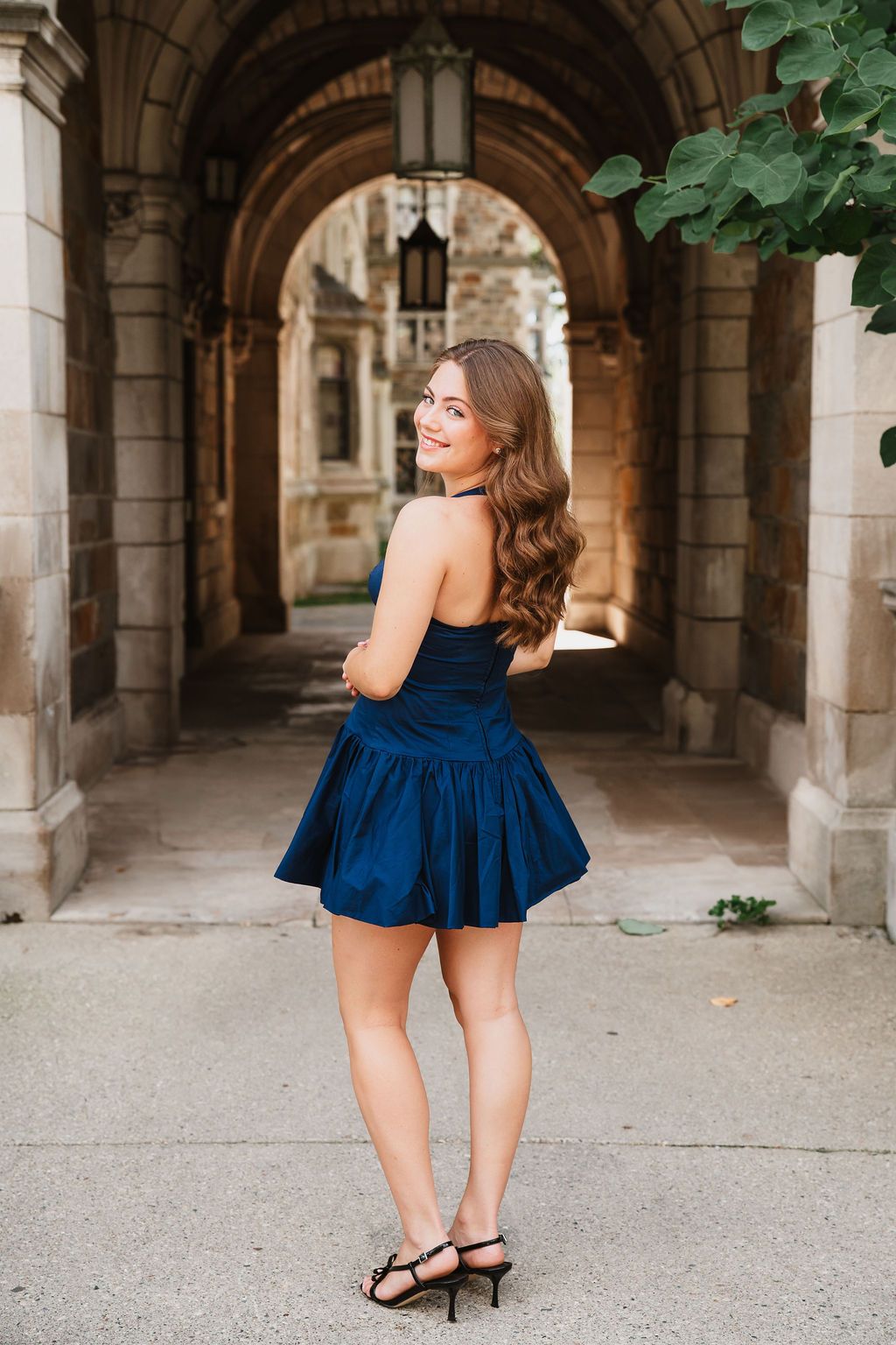 A series of portrait shots showing a navy blue dress against stone archways in an elegant architectural setting.