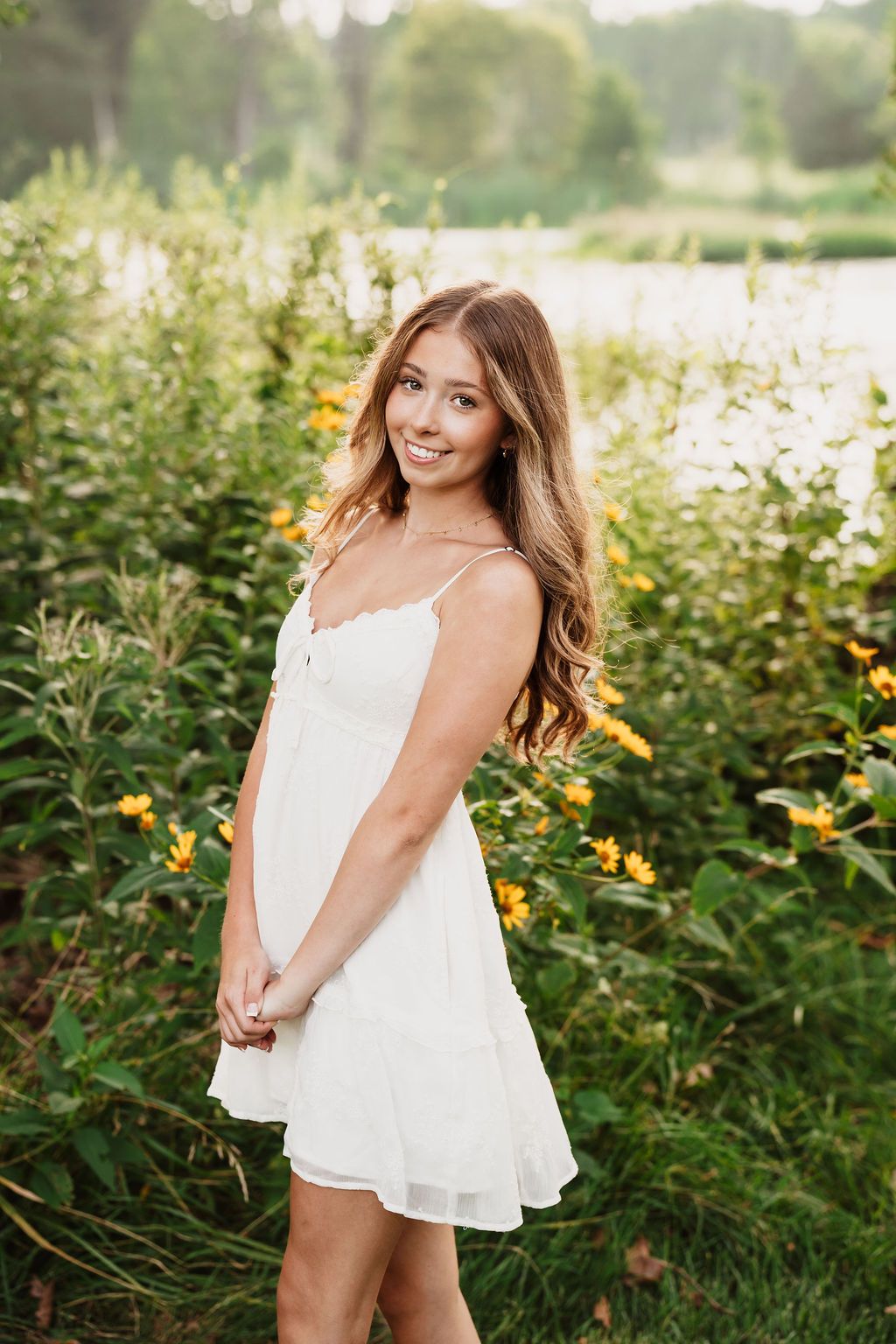 A series of outdoor portrait photographs showing someone in a white summer dress posing in a garden with blooming flowers.